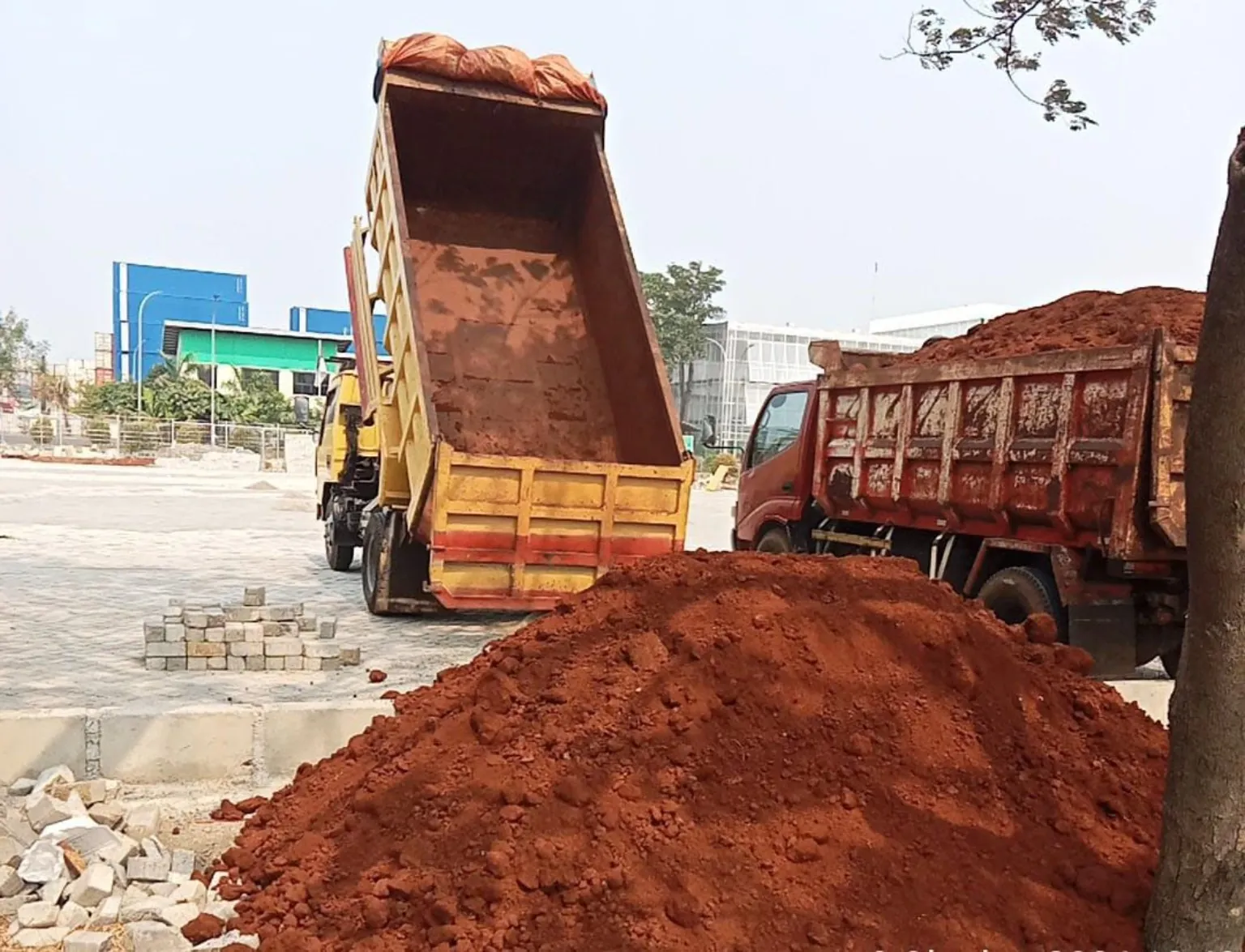 Dump truck menurunkan tanah merah untuk pengurugan lahan
